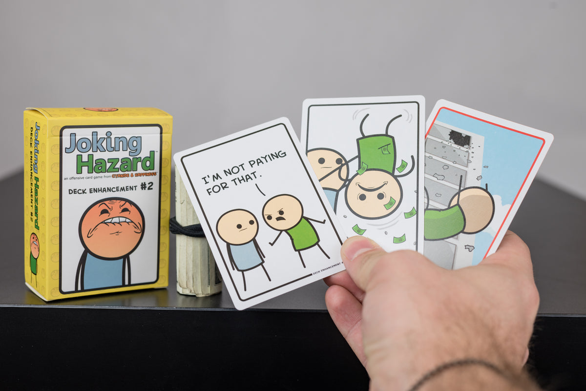 Hand holding Joking Hazard Deck Enhancement #2 cards next to the box